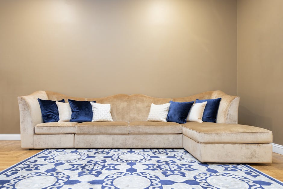 Spacious beige sofa adorned with blue and white throw pillows, set against a neutral wall in a stylish living room.